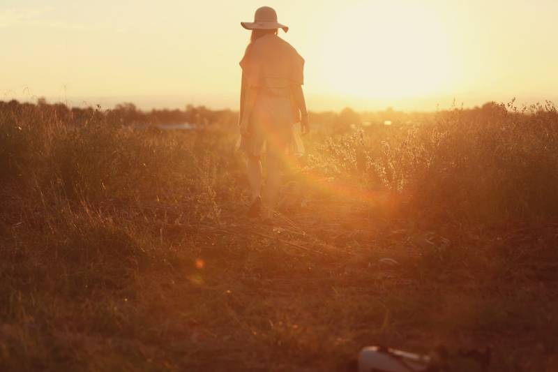 Person, die auf grünem Gras während des Sonnenuntergangs steht