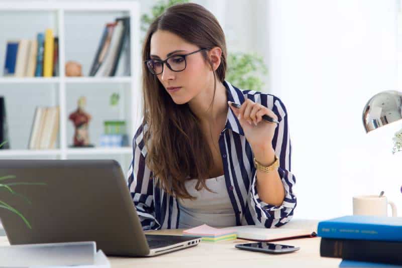 Porträt der schönen jungen Frau, die im Büro arbeitet