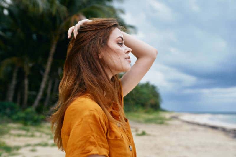 Schöne Frau des roten Haares in einem gelben Sommerkleid auf der Insel