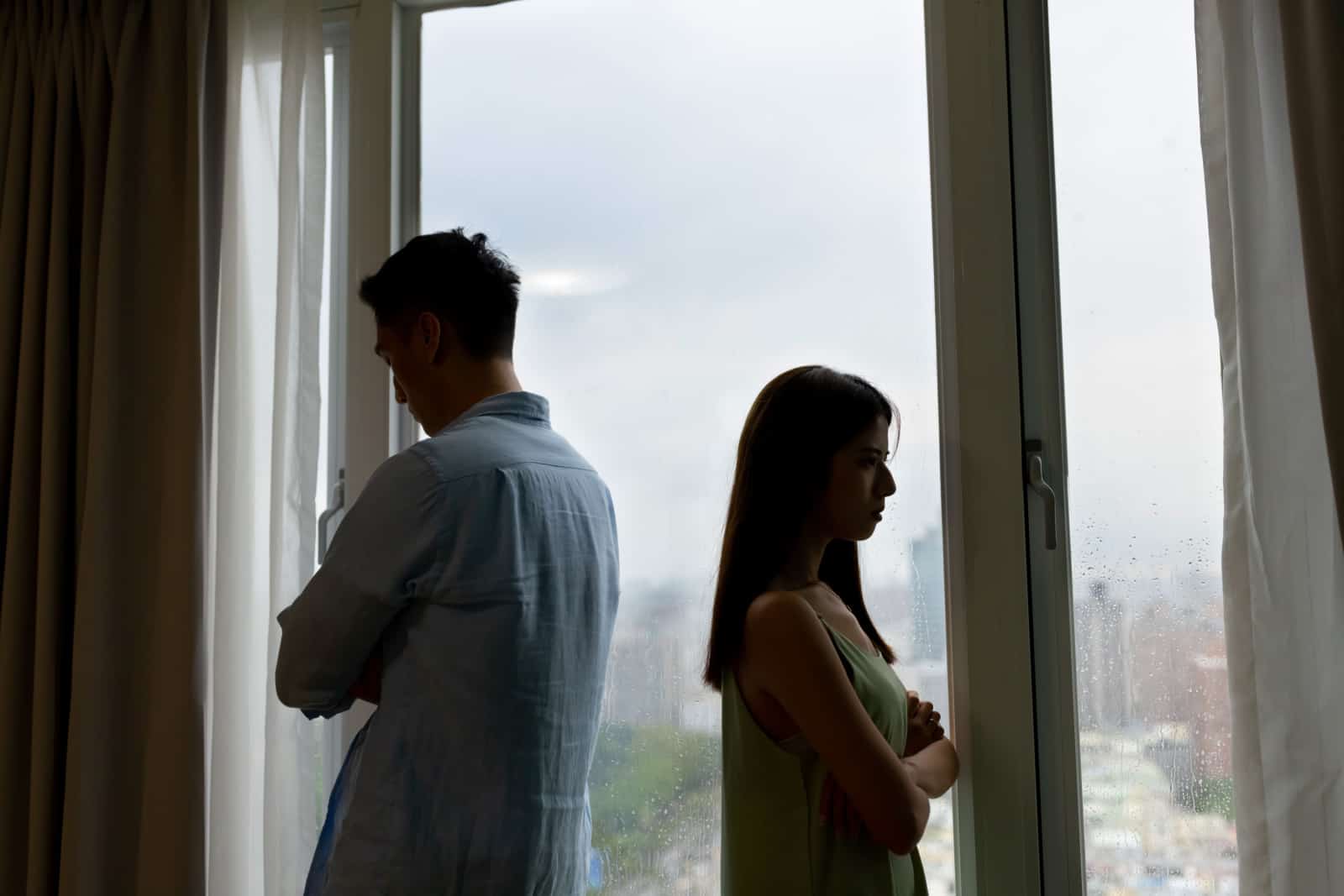 Silhouette eines asiatischen Paares hat einen ernsthaften Streit vor dem Fenster zu Hause