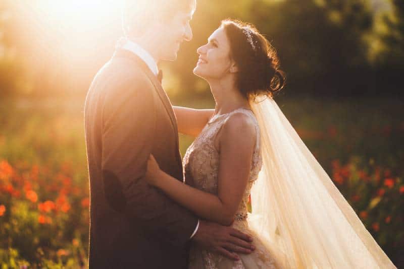 Sonnenscheinporträt der glücklichen Braut und des Bräutigams im Freien