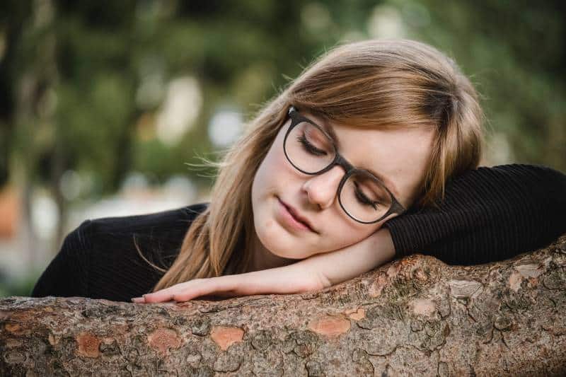 Tilt-Shift-Fotografie der Frau, die auf Baumstamm schläft