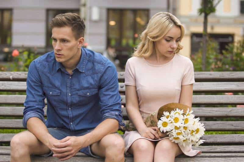 Unglückliches Paar sitzt nach dem Kampf, Mädchen mit Blumen, Problem in der Beziehung