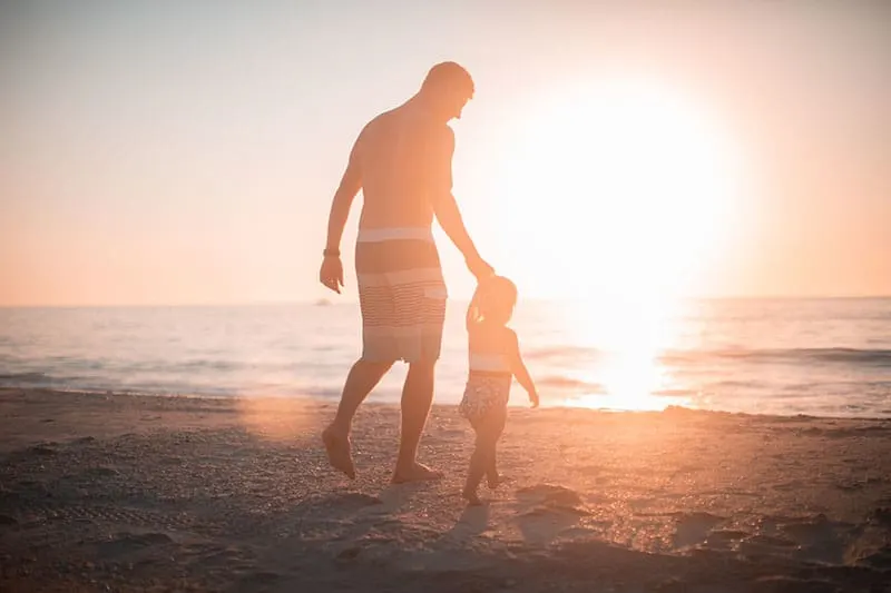 Vater geht mit seinem Kind am Strand spazieren