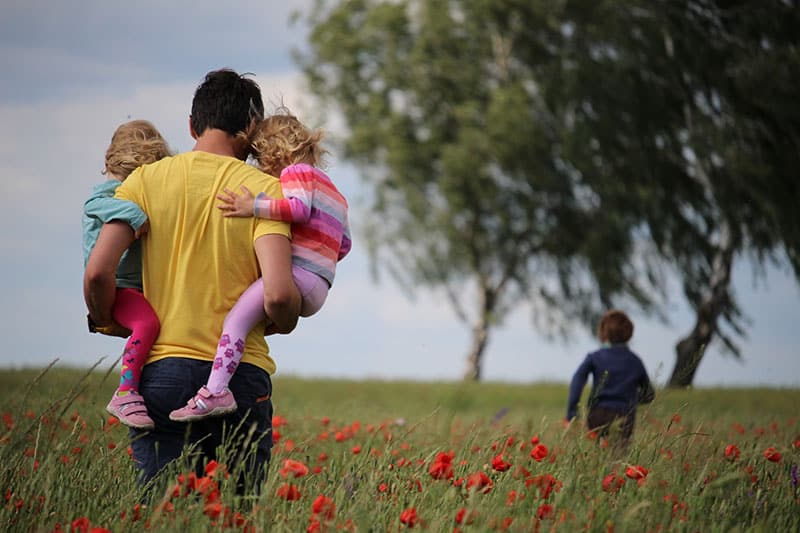 Vater trägt seine Kinder durch Feld