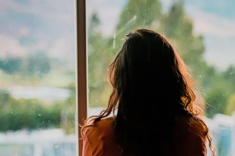 Frau schaut durch Fenster