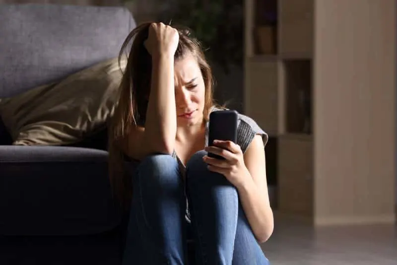 depressive Frau schaut auf ihr Handy