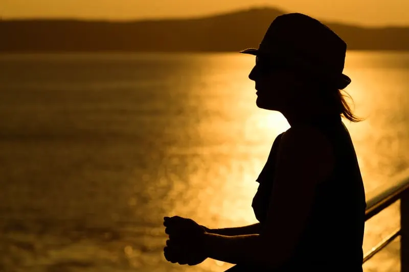 eine Frau mit einem Hut bei Sonnenuntergang