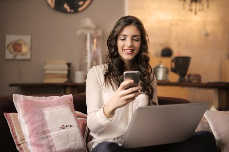 glückliche Frau am Telefon und am Laptop