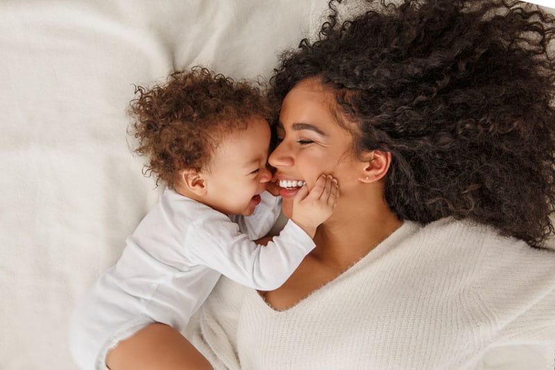 glückliches Baby, das das Gesicht ihrer Mutter berührt