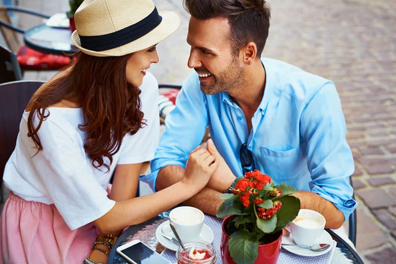glückliches Paar, das ihre Hände im Café hält