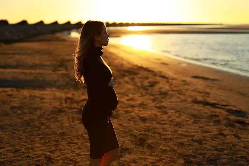 junge schwangere Frau, die am Strand steht