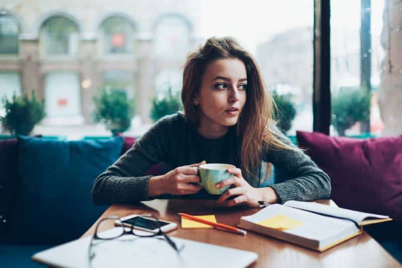 junges Mädchen an der Kaffeebar, die Fenster betrachtet