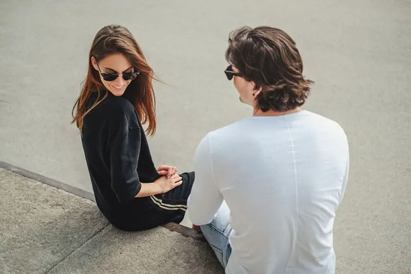 junges Paar mit Sonnenbrille sitzt auf dem Boden