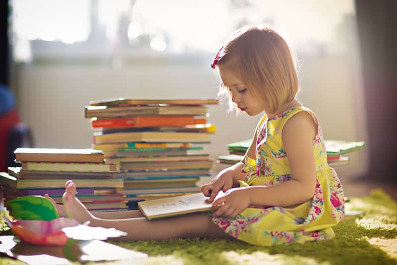 kleines blondes Mädchen, das ein Buch liest