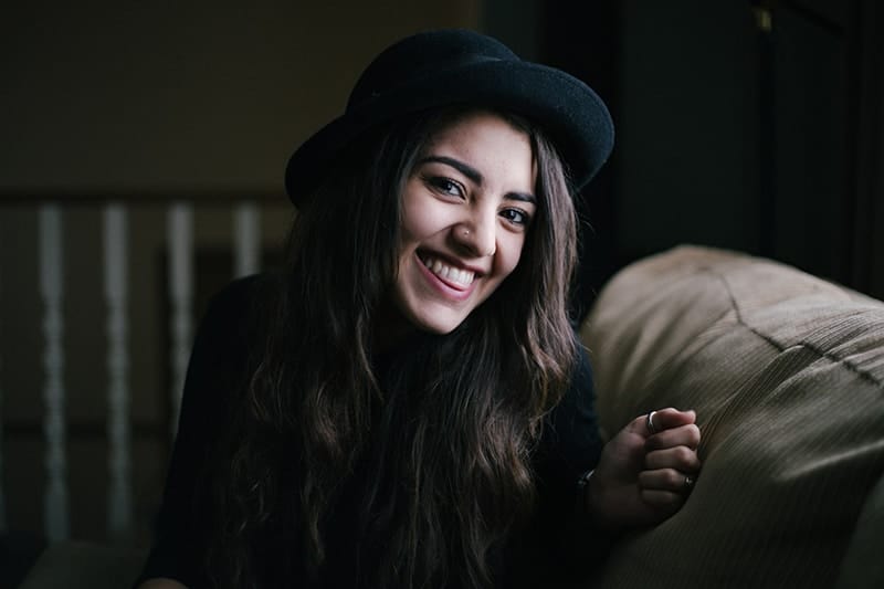lächelnde Frau mit schwarzen Haaren und schwarzem Hut