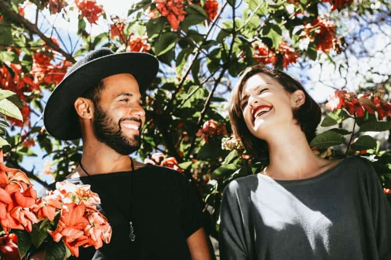 lächelndes Paar umgeben von den Blumen