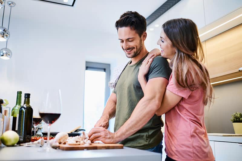 lächelnde Männer, die für seine Frau kochen