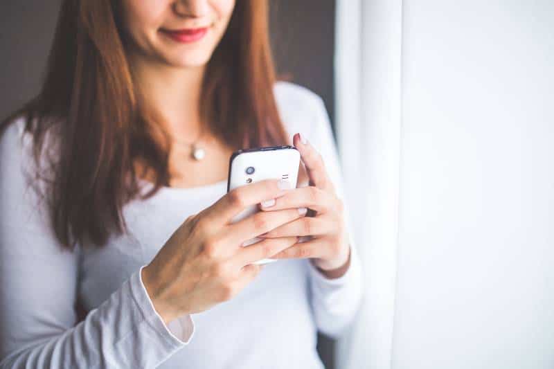 lächelndes Mädchen, das zu Hause SMS schreibt