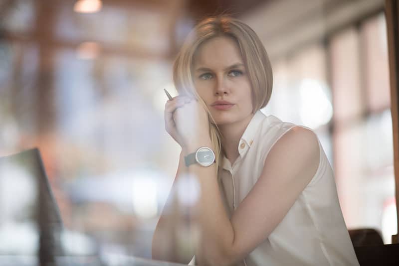 nette blonde Frau, die im Büro denkt