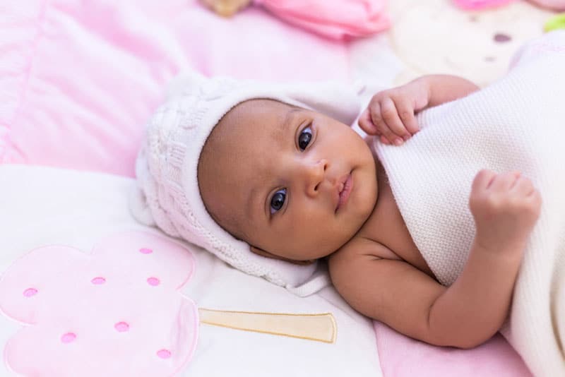 schönes Baby, das auf rosa Bett liegt