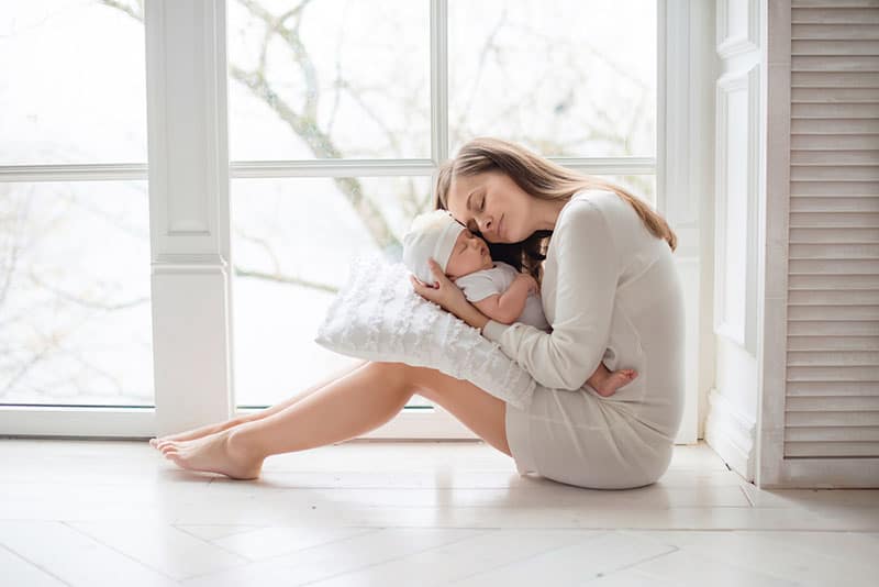 stolze Mutter umarmt ihr neugeborenes Baby
