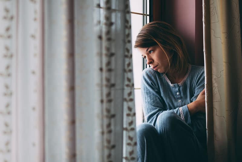 traurige Frau, die durch das Fenster nach draußen schaut