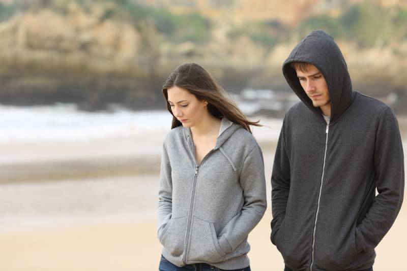 unglückliches Paar am Strand spazieren