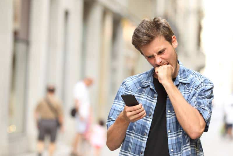 wütender Mann, der Telefon ansieht