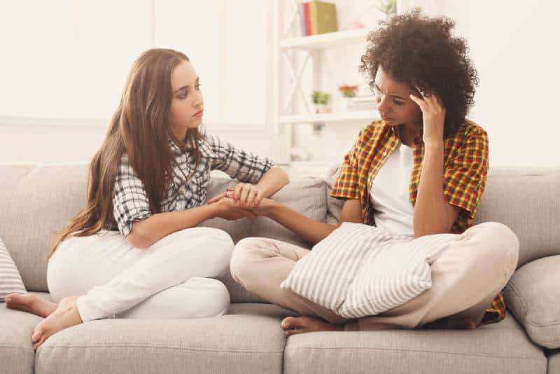 zwei Frauen, die über Probleme sprechen, während sie zu Hause auf dem Sofa sitzen