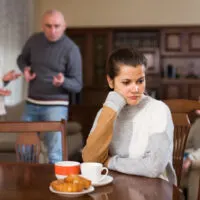 Porträt einer verärgerten Frau, die nach Streit mit Ehemann und seinen Eltern zu Hause am Tisch sitzt