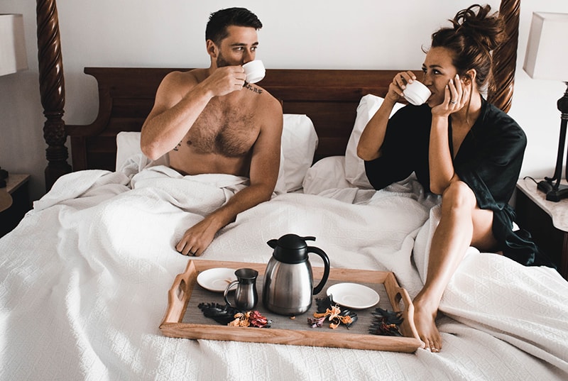  Die Frau bereitete dem Mann, der im Bett saß, Kaffee und Frühstück zu