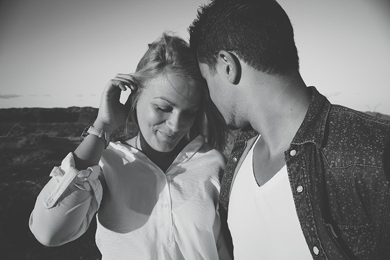 Ein Mann flirtet mit einer Frau, während er ihr ins Ohr flüstert