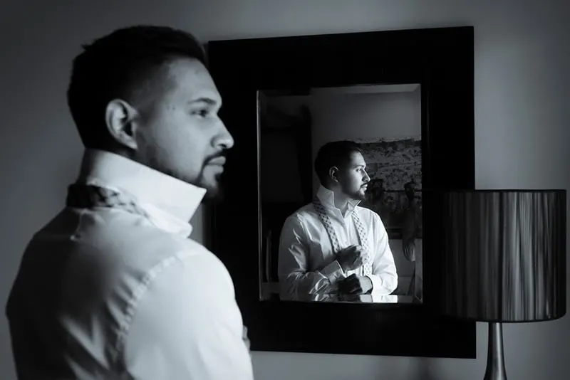 Ein Mann faltete sein Hemd, während er vor dem Spiegel stand