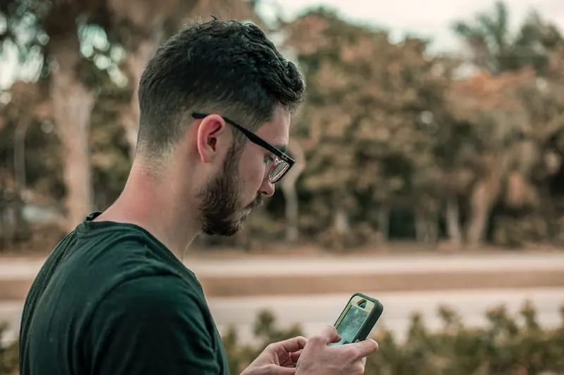 Ein Mann liest eine Nachricht vom Smartphone während des Stehens
