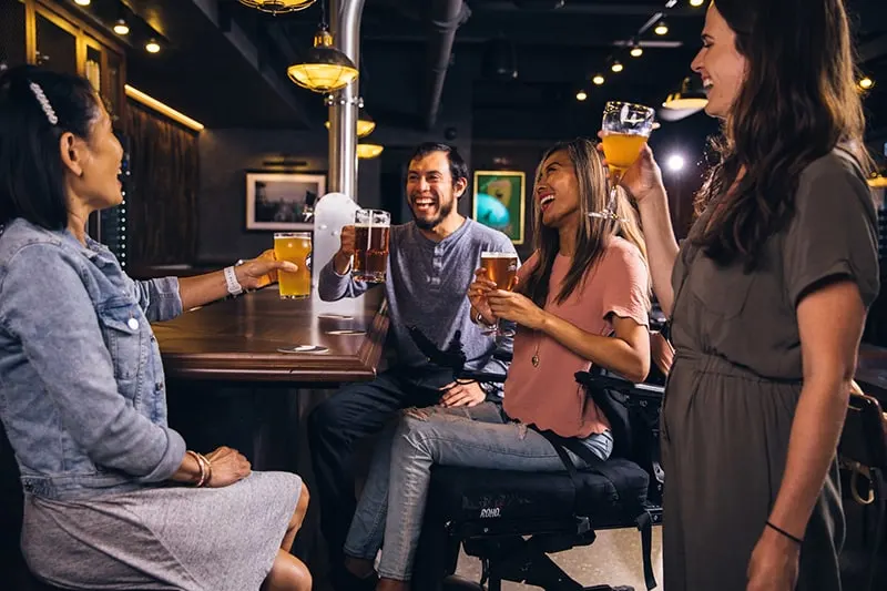 Ein Mann trinkt mit drei Frauen an der Bar