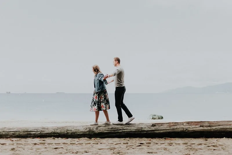  Ein Mann und eine Frau gehen am Strand entlang Während der Tageszeit