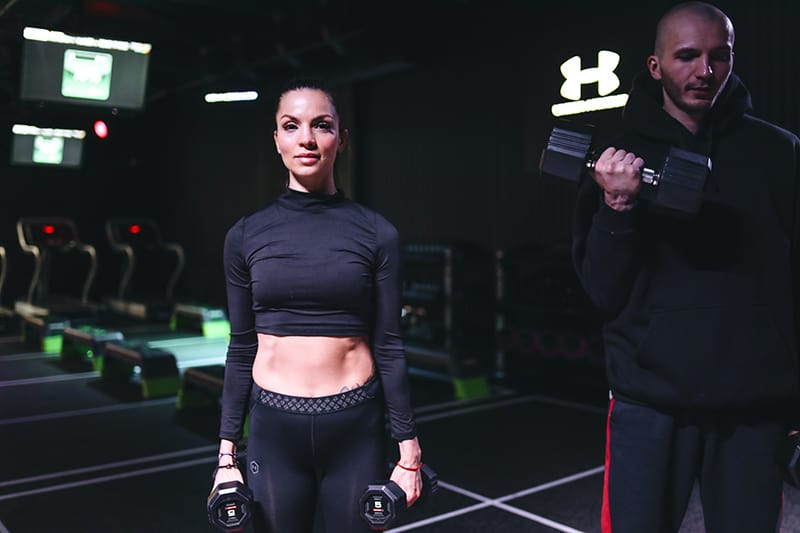 Ein Mann und eine Frau halten Hanteln, während sie Zeit miteinander im Fitnessstudio verbringen