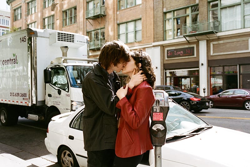 Ein Mann und eine Frau küssen sich im Stehen an einem öffentlichen Ort