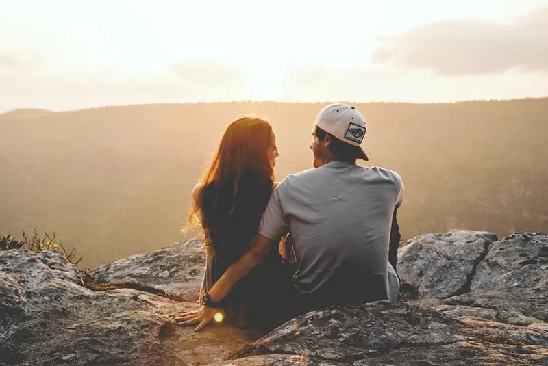 ein Mann und eine Frau sitzen auf dem Felsen während des Sonnenuntergangs
