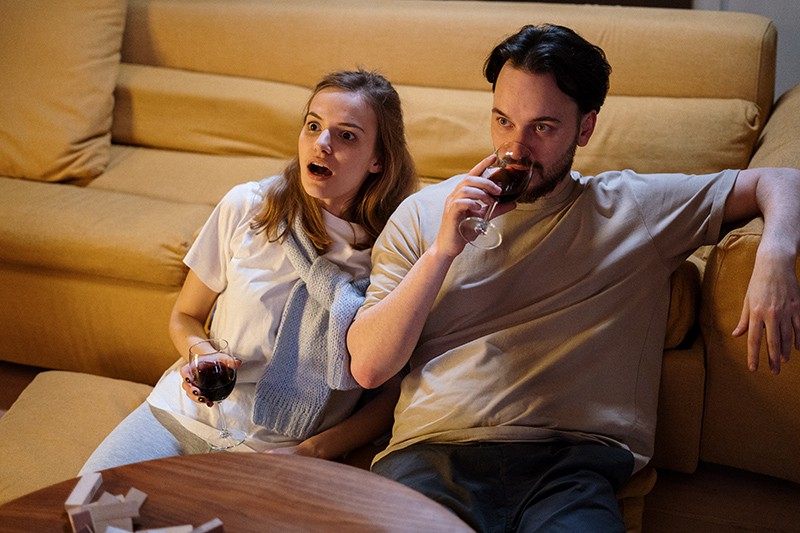 Ein Paar trinkt Wein, während es zu Hause einen Film sieht