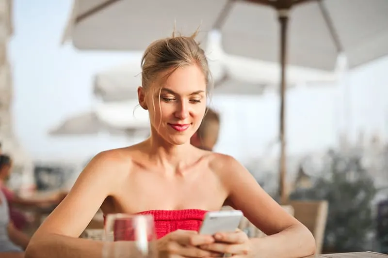 Eine selbstbewusste Frau benutzt ein Smartphone, während sie in einem Café sitzt