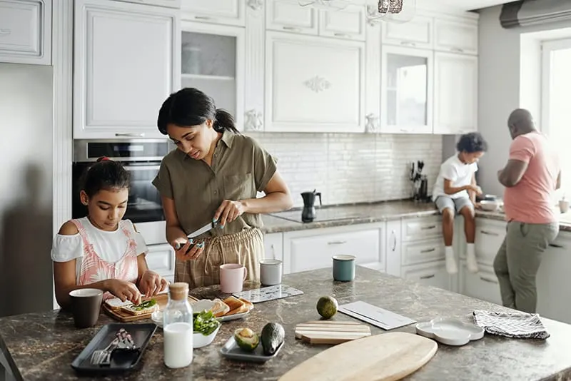 Eltern bereiten mit ihren Kindern Essen in der Küche zu
