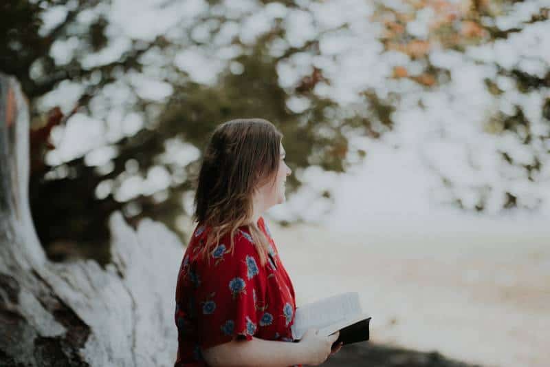 Frau hält Buch im Freien