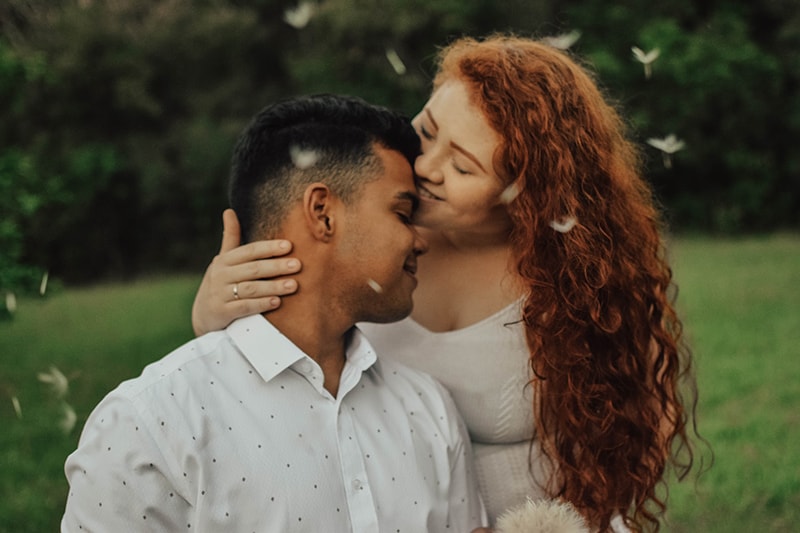  Frau küsst Mann in der Stirn in der Natur