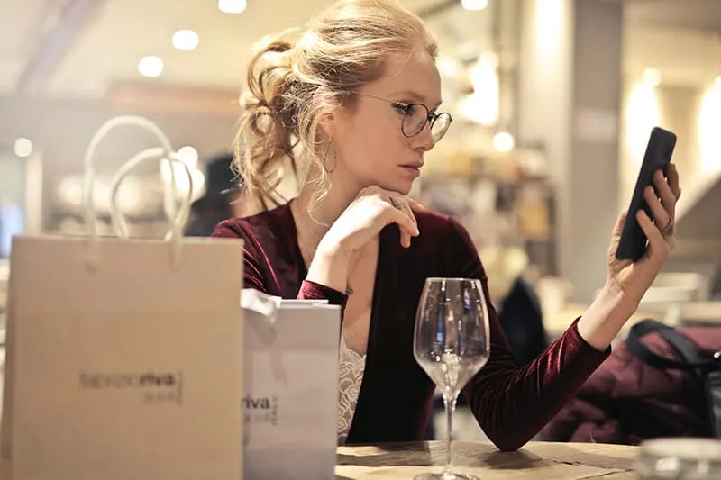  Frau mit ihrem Smartphone beim sitzen am tisch