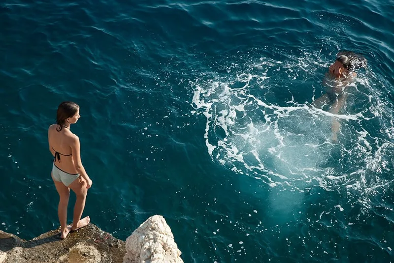  eine Frau, die auf der Klippe steht und ins Meer springen will