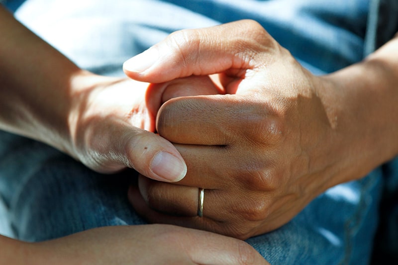 Frau tröstet Mann, während er seine Hand drückt