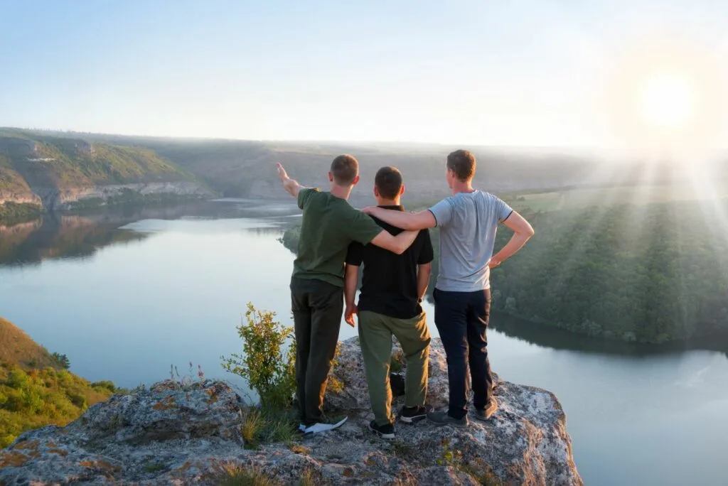 Freunde stehen auf einem Felsen und blicken in die Ferne
