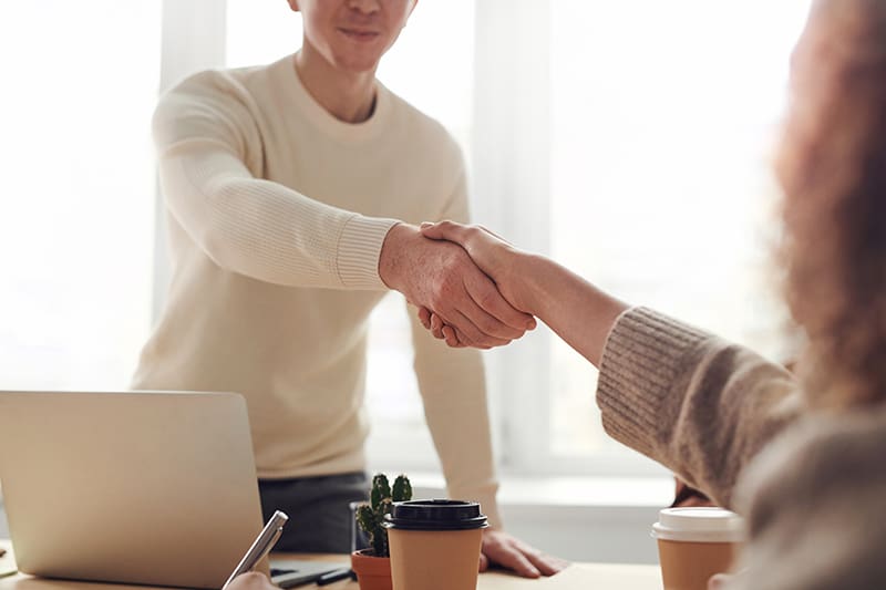 Mann und Frau geben sich im Büro die Hand